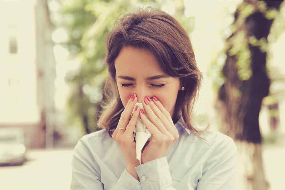 woman blowing nose sneezing