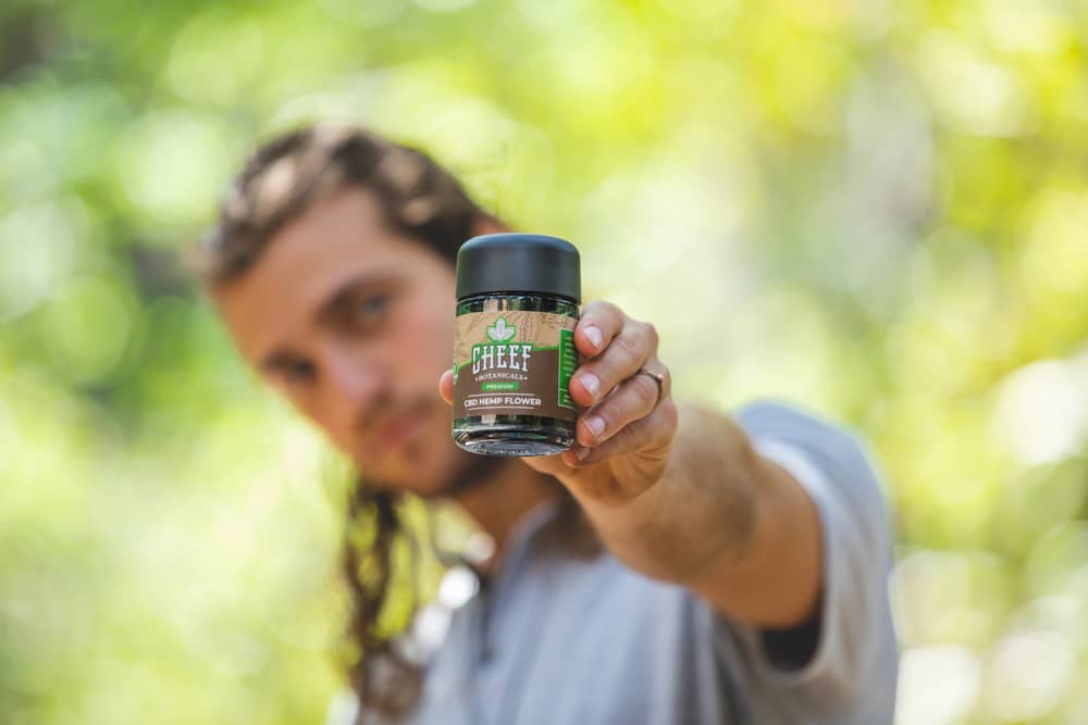 holding hemp flower jar towards camera