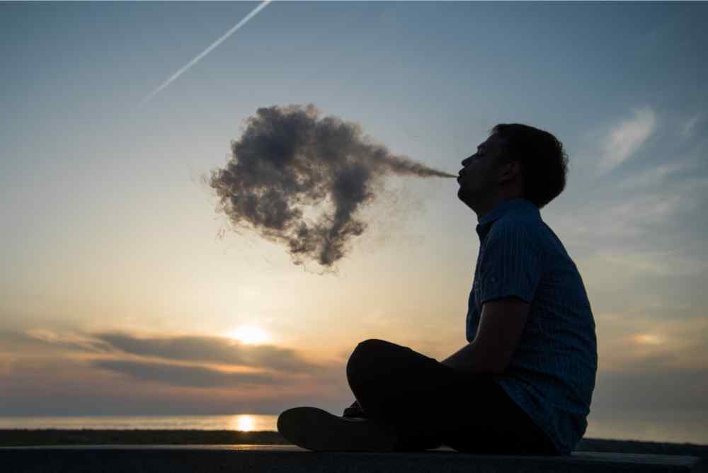 man vaping clouds near clouds