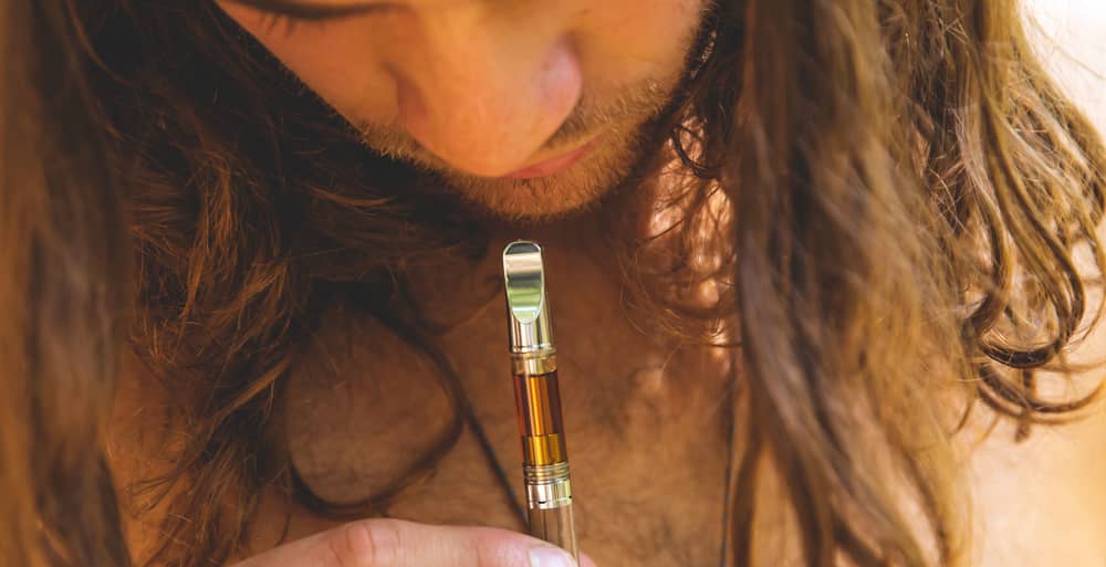 man with long hair vaping