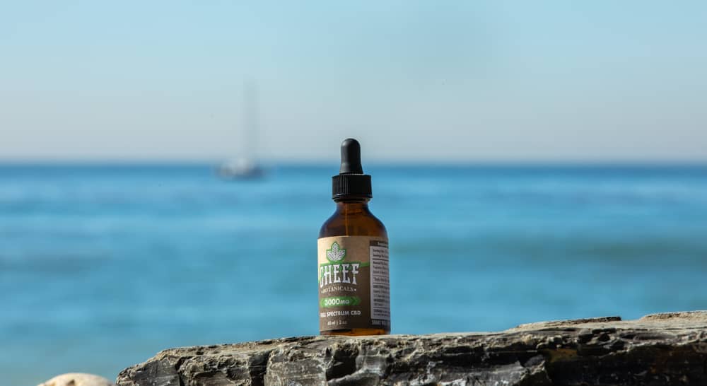 cbd oil bottle at beach against water