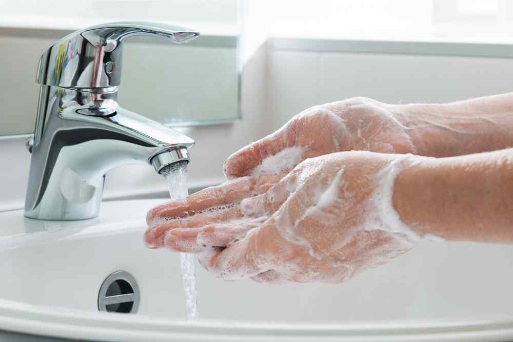 two hands rubbing soap together under water