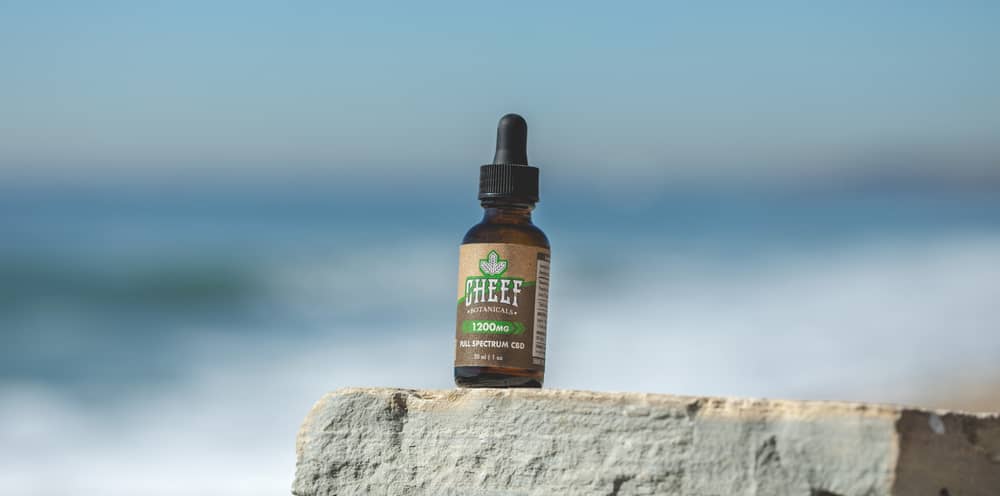 cbd tincture bottle at beach on rock