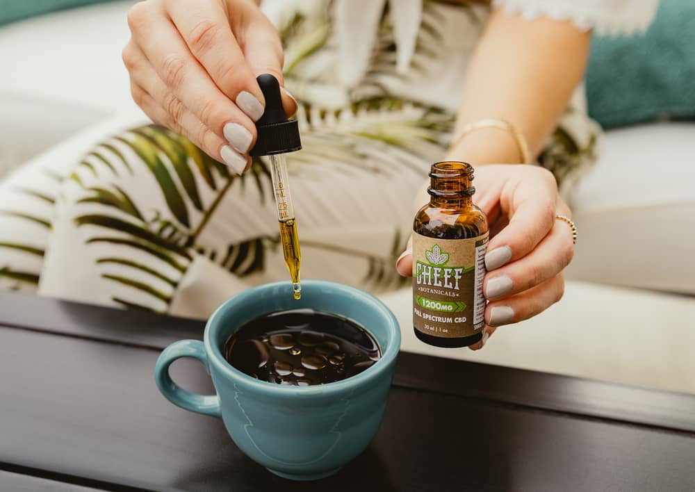 woman putting cbd oil into her coffee