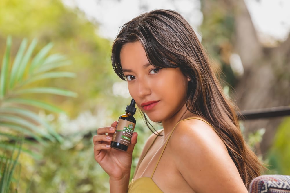 woman holding up cbd oil to face