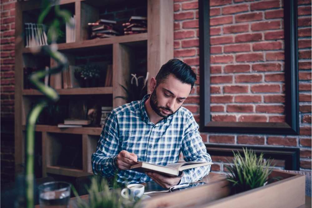 man reading book in coffee shop