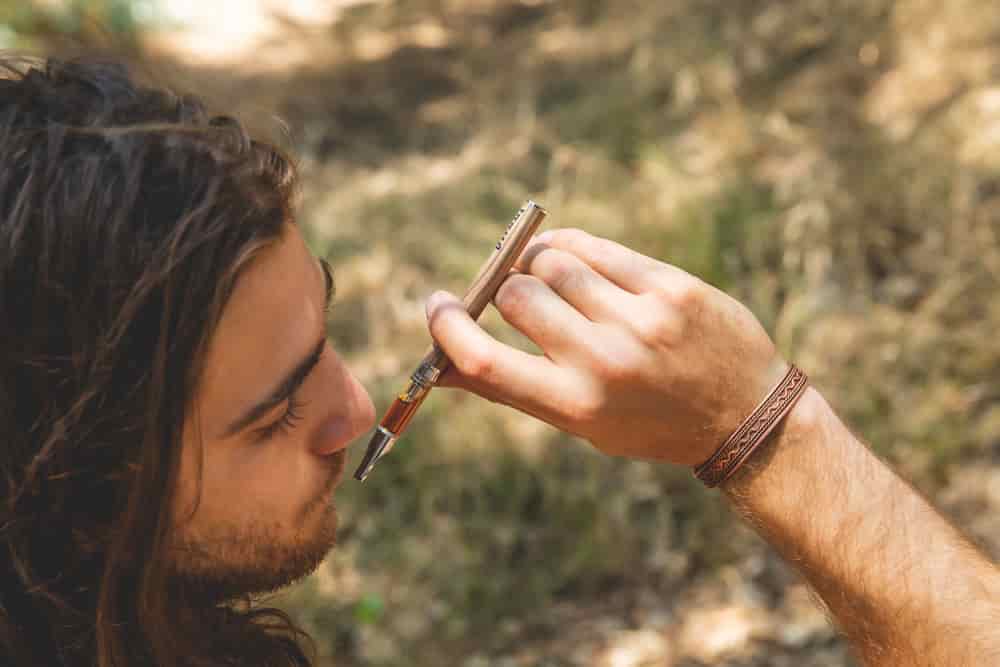 hippie dude using a vape pen