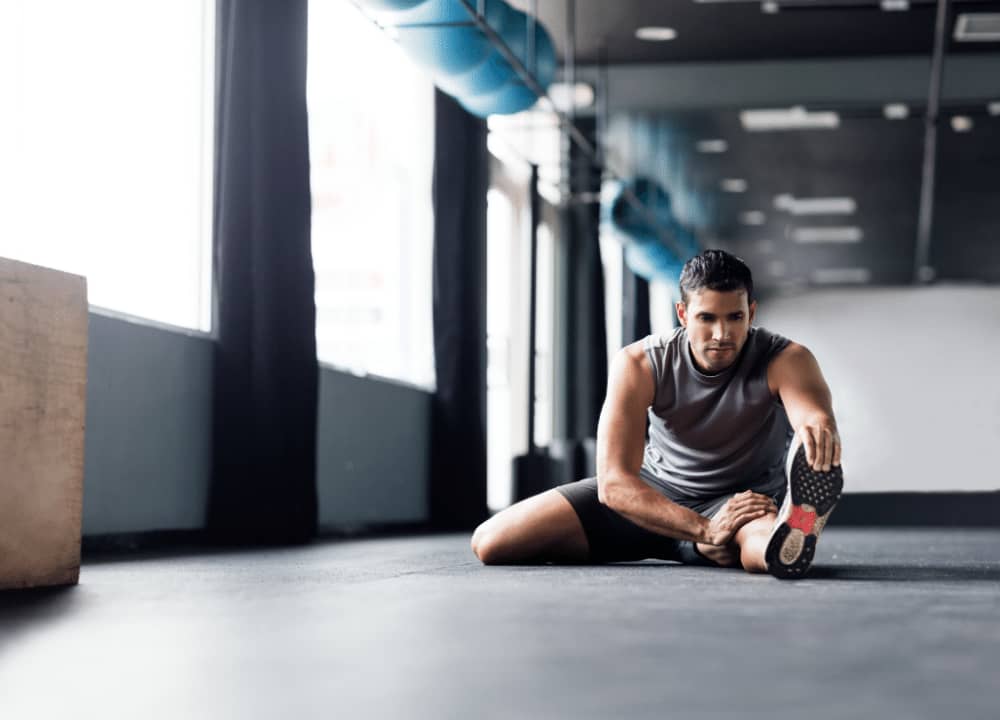 young man in gym stretching legs