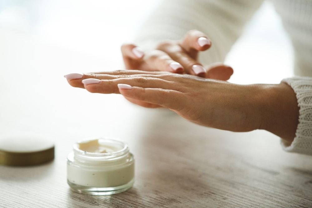 woman applying hand cream from jar