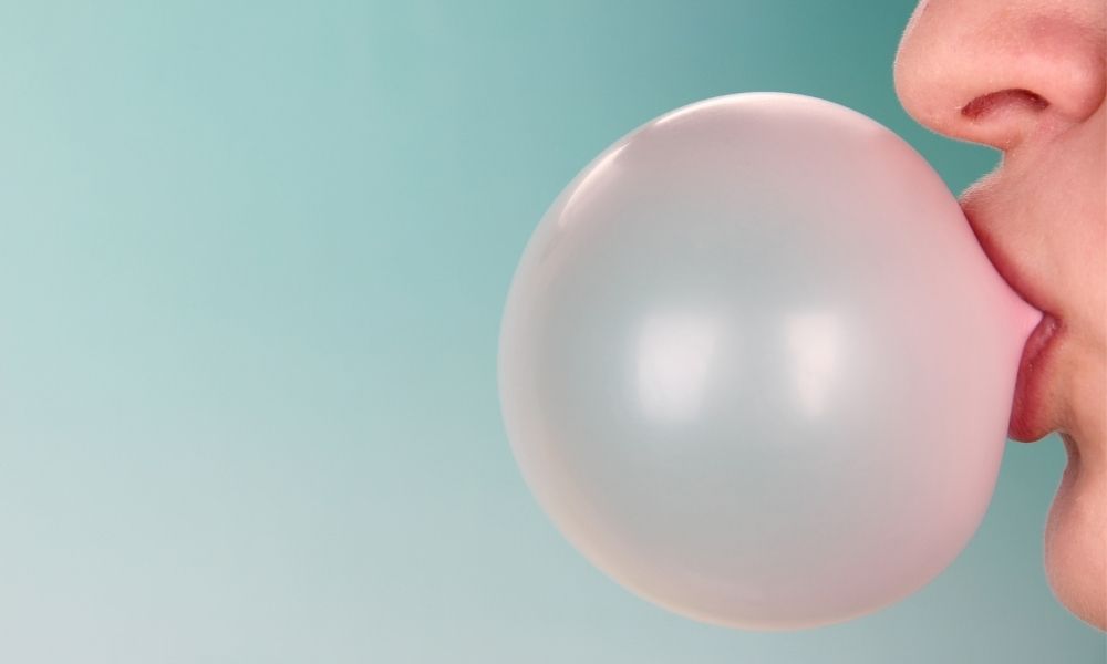 woman blowing large pink bubble