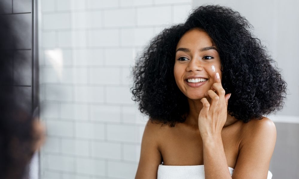 woman applying face cream in mirror