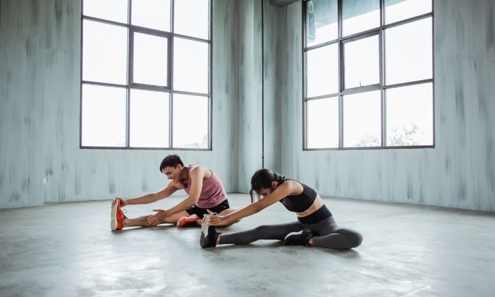 two athletic people stretching indoors