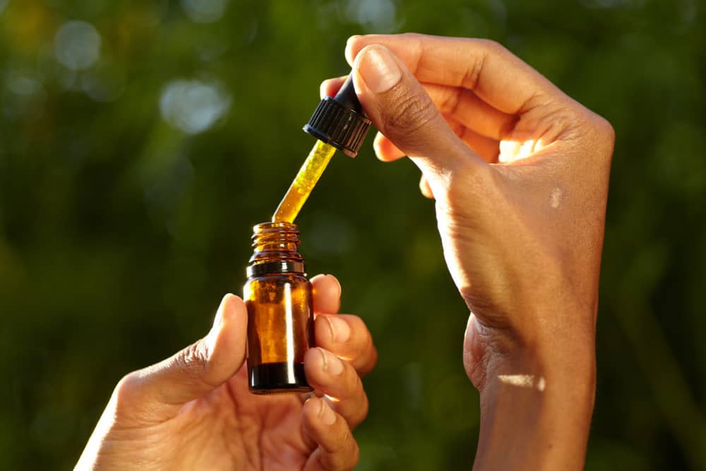 person using a cbd oil dropper bottle