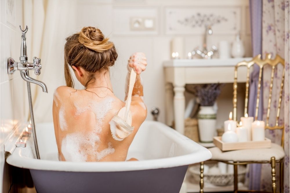 woman taking a bath and scrubbing her back