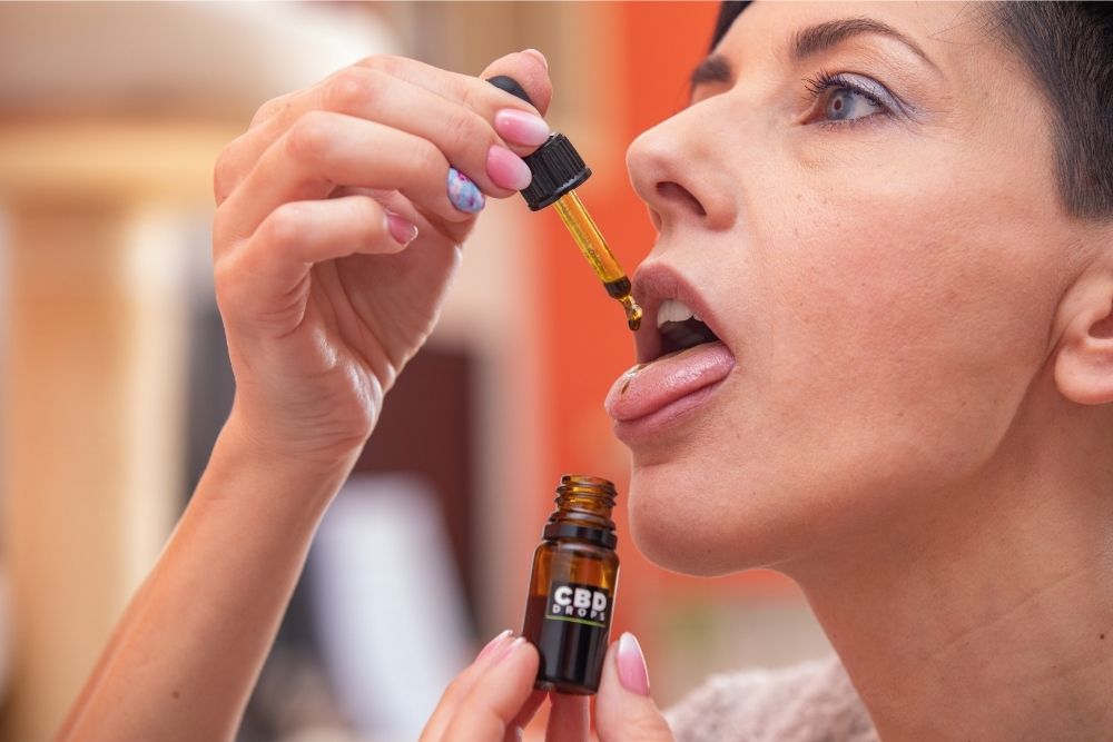 lady dropping cbd onto tongue