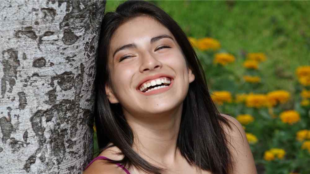 woman laughing next to tree