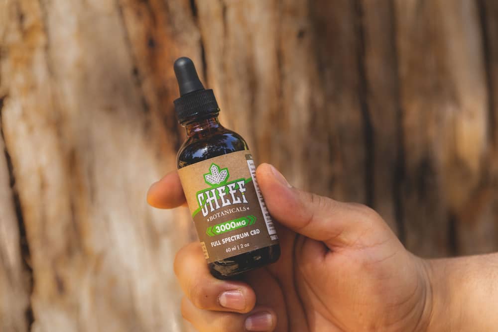 cbd tincture in hands with tree