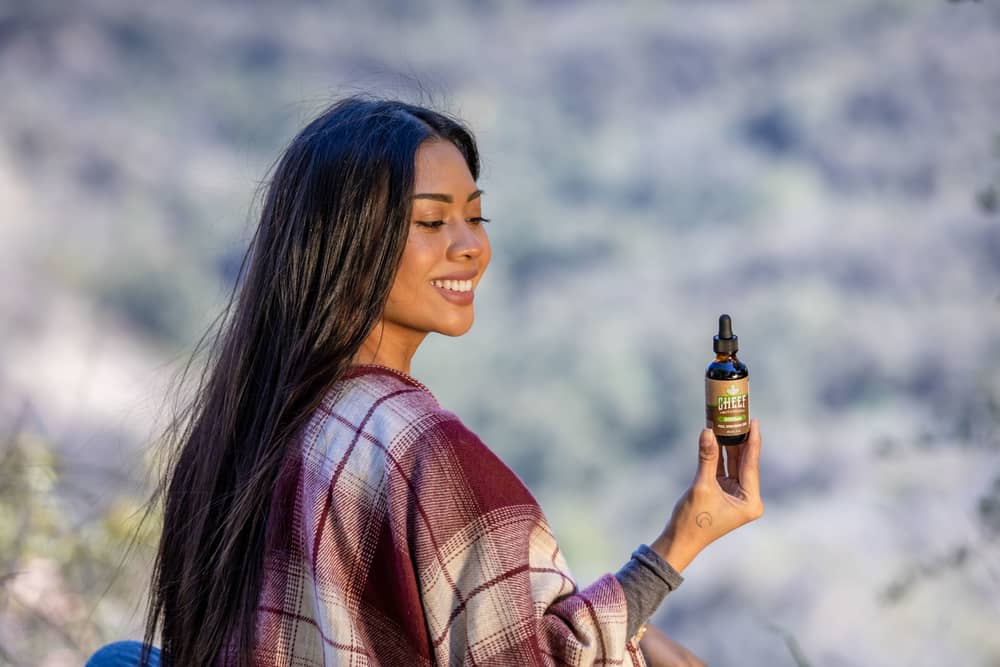 girl holding cbd oil in nature