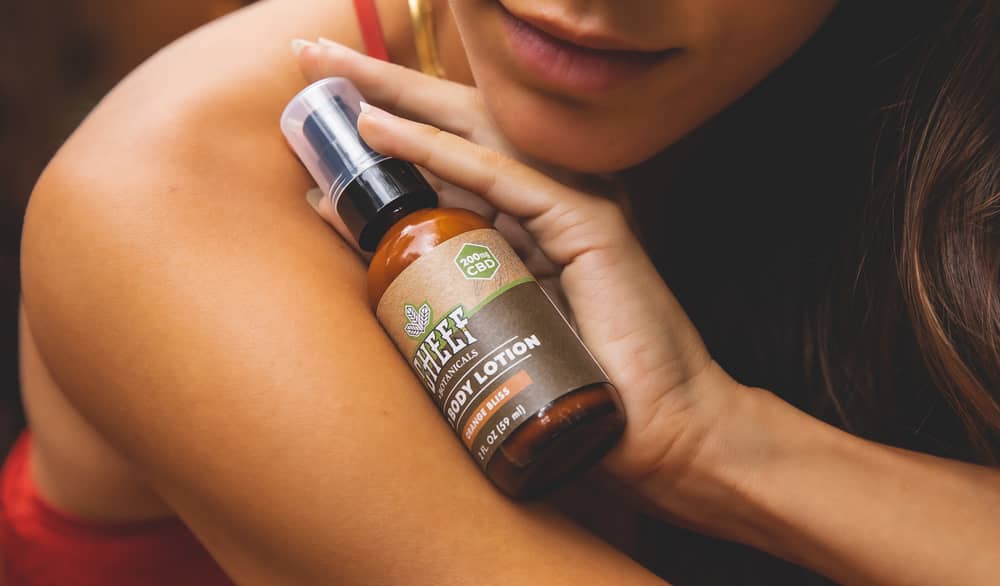 woman holding bottle of cannabidiol lotion