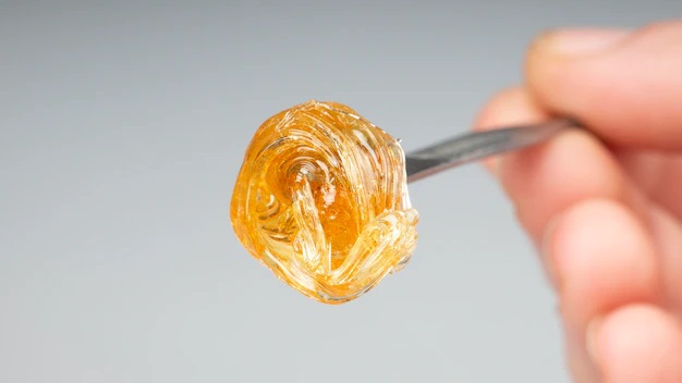 live resin vs distillate person holding concentrate with dab tool.