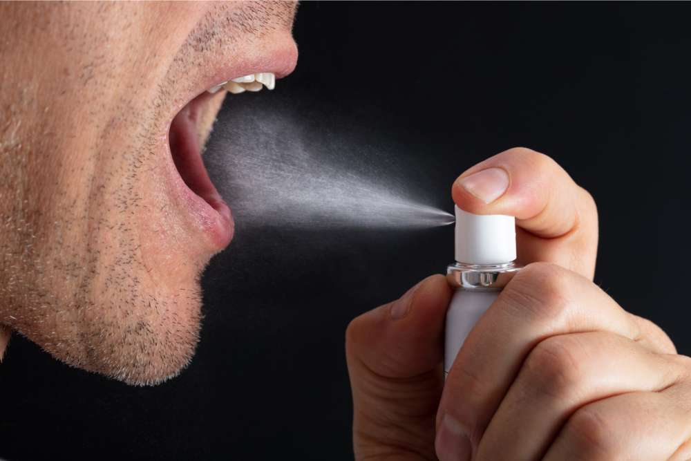 man spraying cbd oral spray in mouth