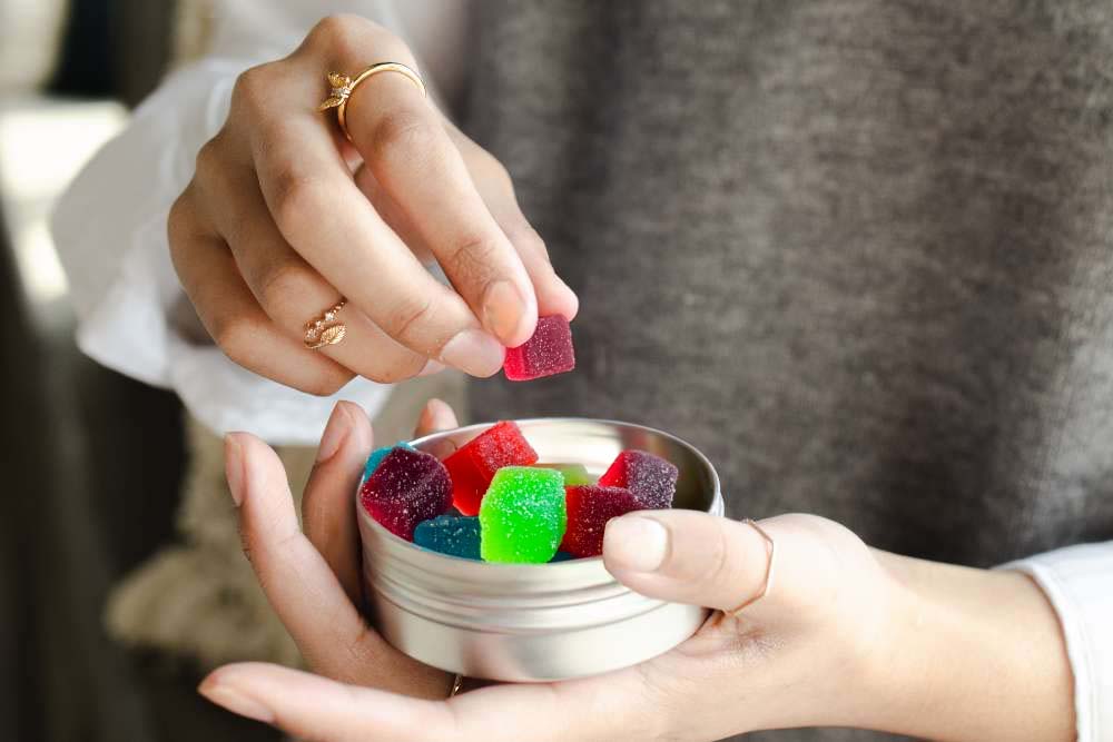 person taking thcp gummy cubes out of tin