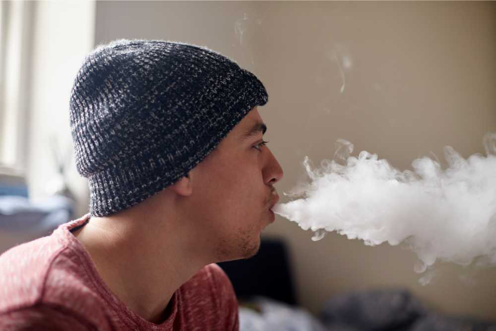 man exhaling big puff of smoke