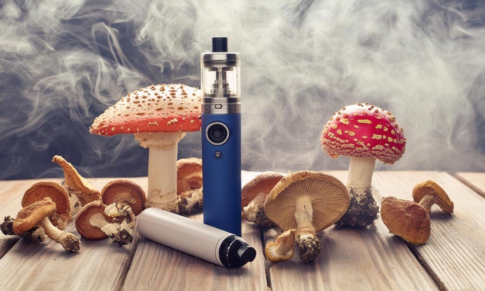 dried amanita muscaria mushrooms and two vapes on a wooden table with vapors in the air 