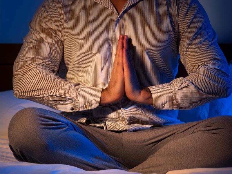 up close view of a man meditating in a dimly lit room