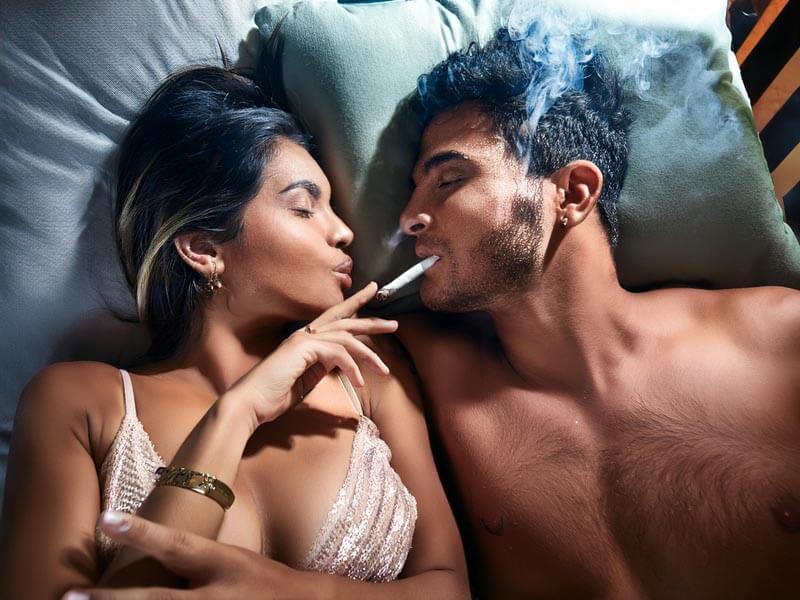 couple sharing a cannabis joint in bed and they're about to get intimate