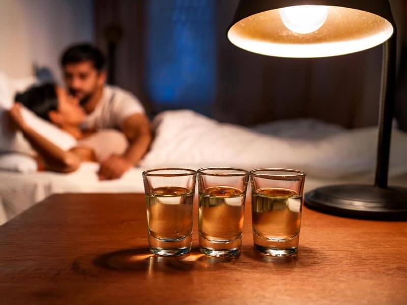 couple being intimate with alcohol shots nearby