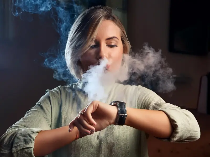 a woman blowing smoke out of her mouth and looking at her watch